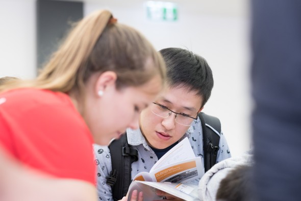 Zwei Studierende schauen sich eine Informationsbroschüre an